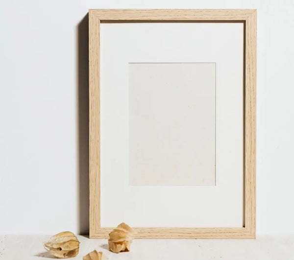 Natural wood color frame with white matting placed on the floor